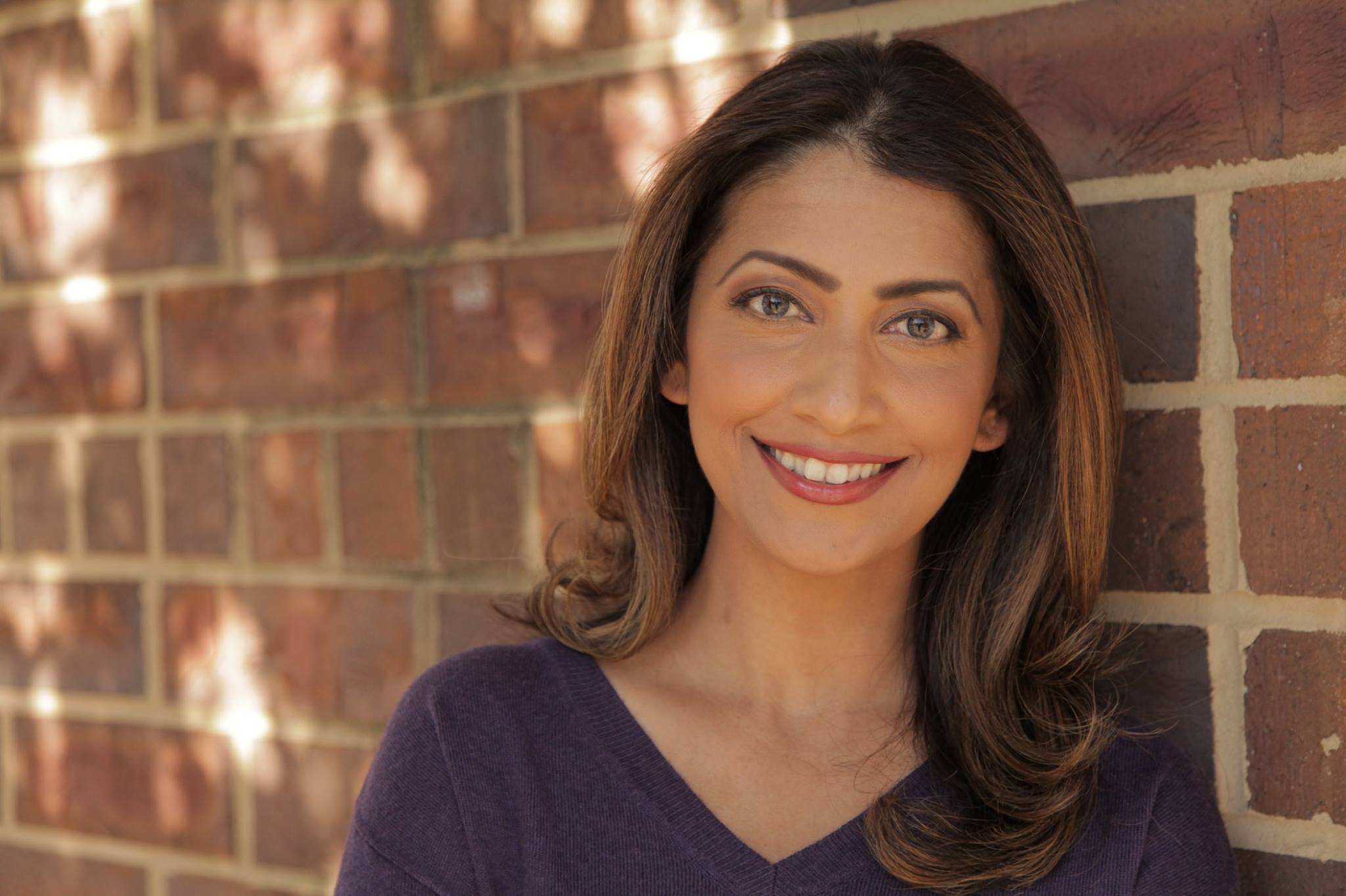 Sanam Azeem professional headshot against brick wall
